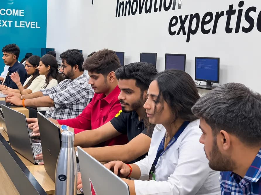 A row of students on laptops under the "passion, innovation, expertise" wall