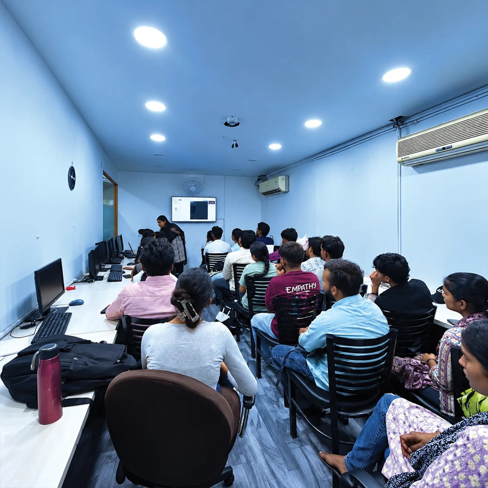 Students following a trainer's on-screen walkthrough in the seminar room