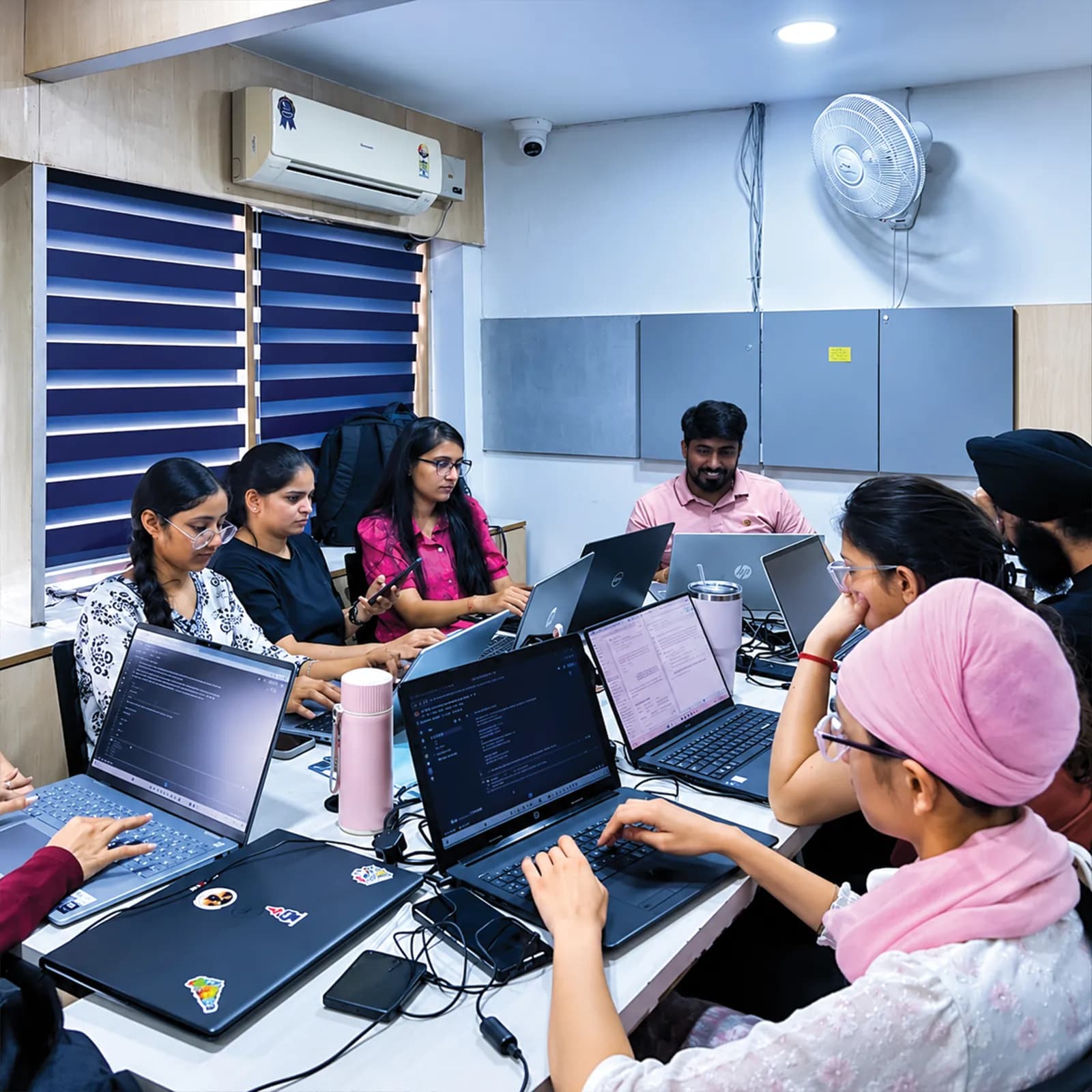 Students coding together on laptops around a shared table